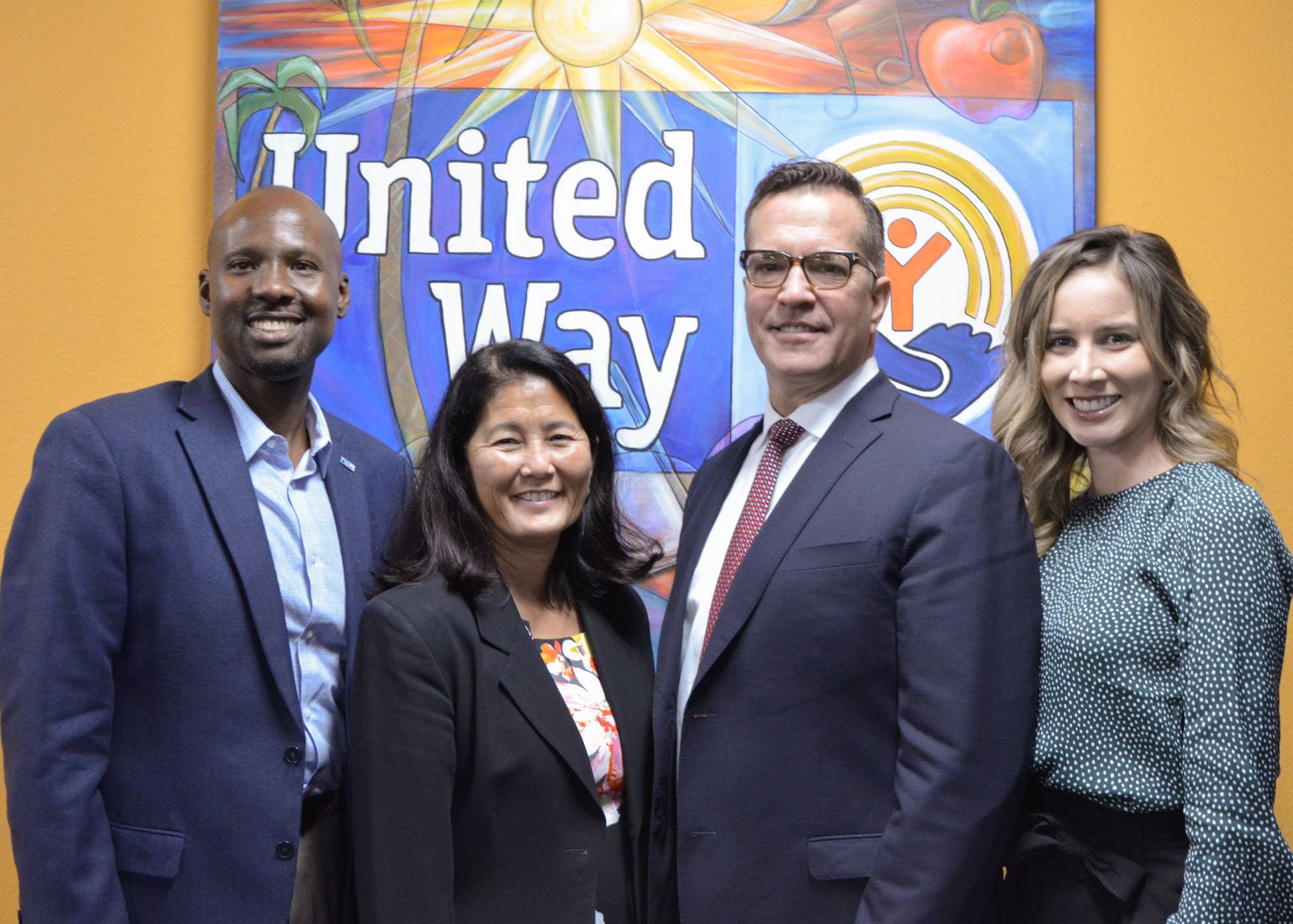 four people standing in front of a United Way sign