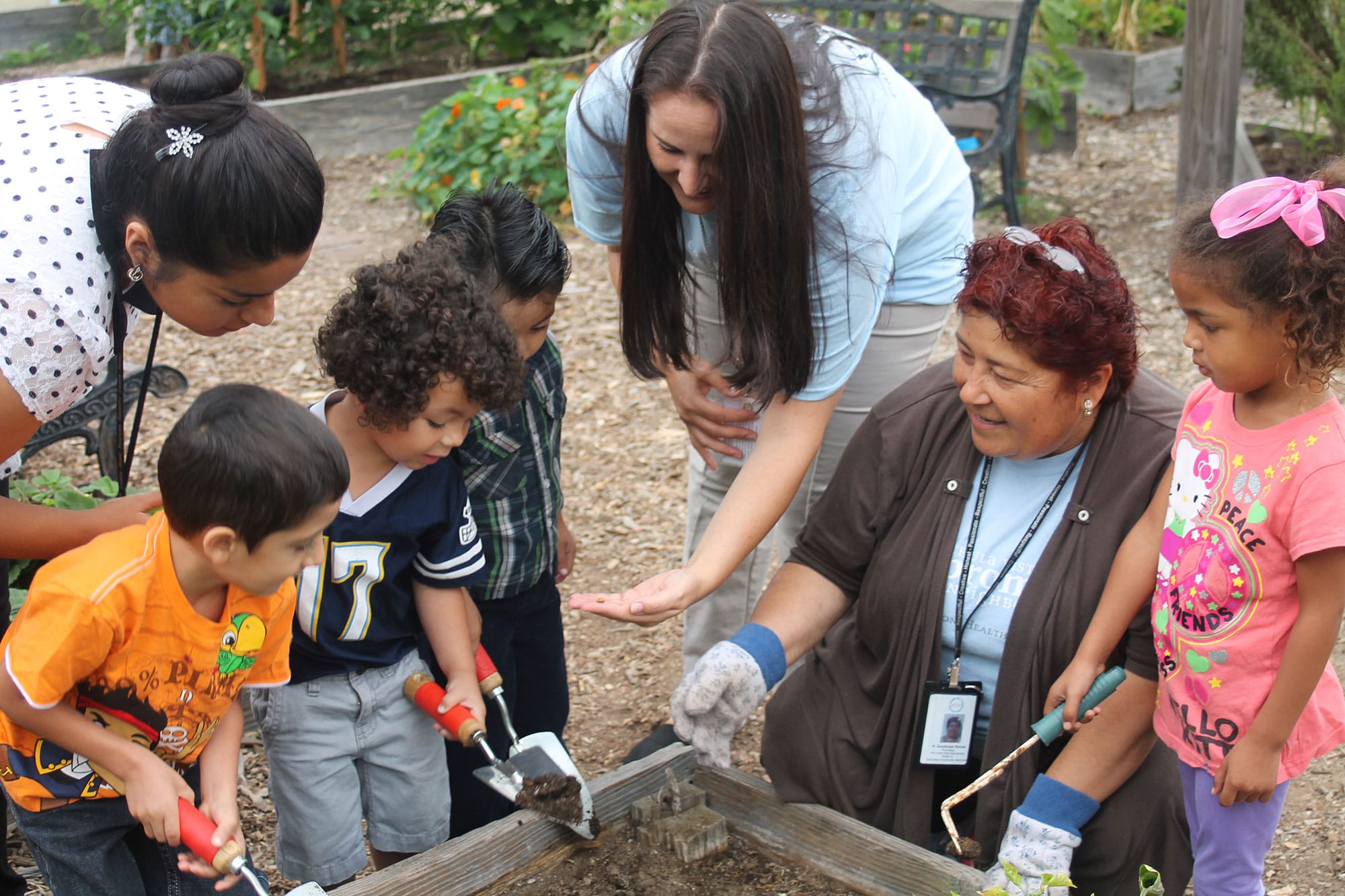 Adults help children in a garden