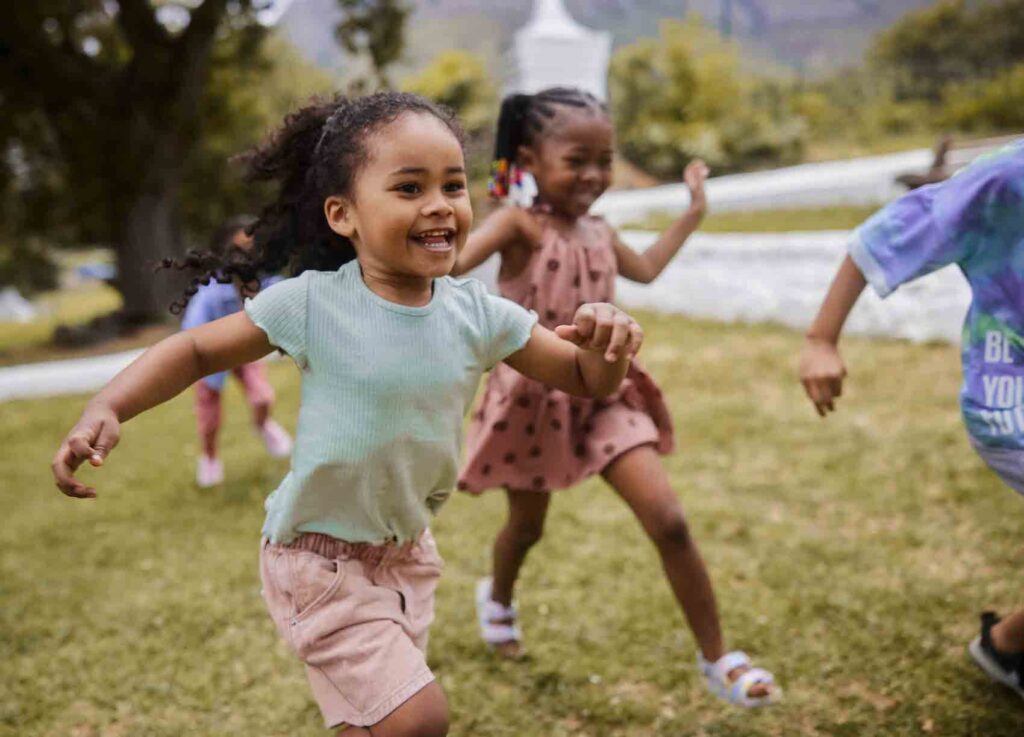 Diverse young children running in grass laughing