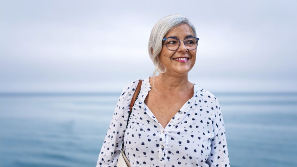 Middle-aged woman smiling with the ocean in the background