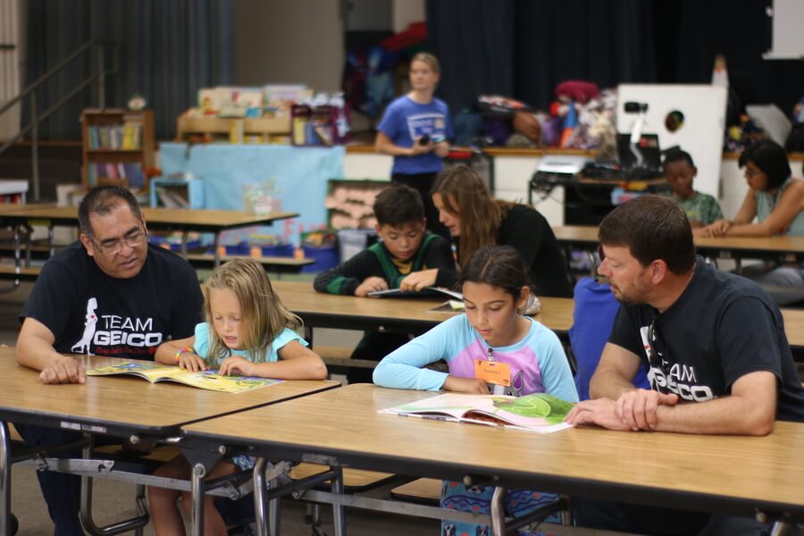 Volunteers reading books to elementary school children during an event with United Way of San Diego County