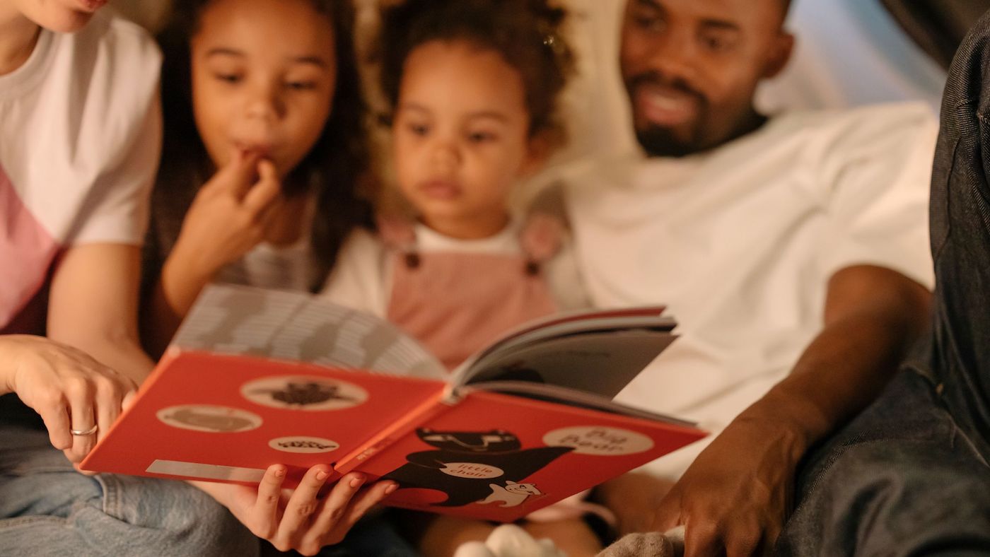 mother and father reading to their two young daughters before bedtime
