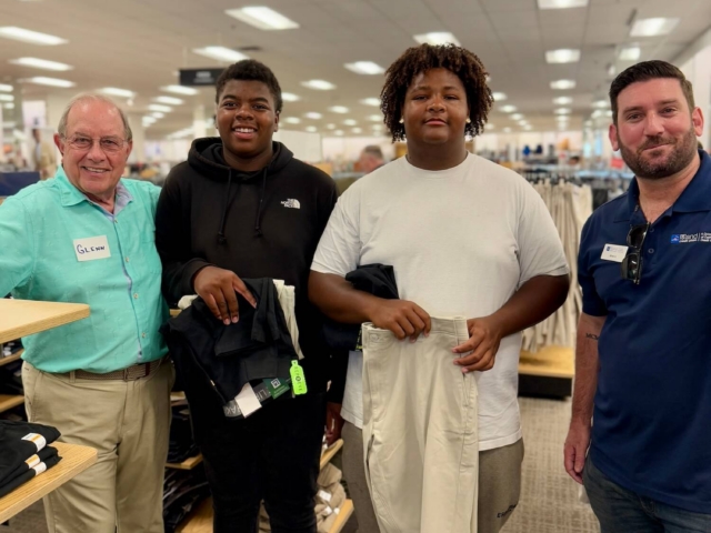 IMG_3247 Two male volunteer mentors and two male students smile during a shopping event for professional clothing