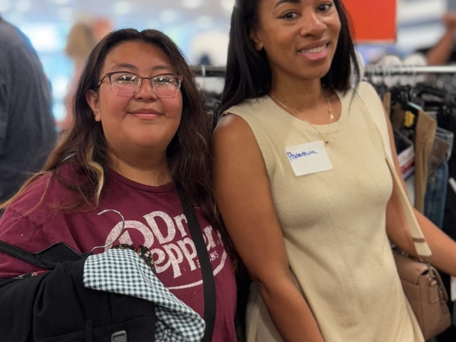 IMG_3286 2 female teen and female volunteer holding hangers of clothing during a shopping event